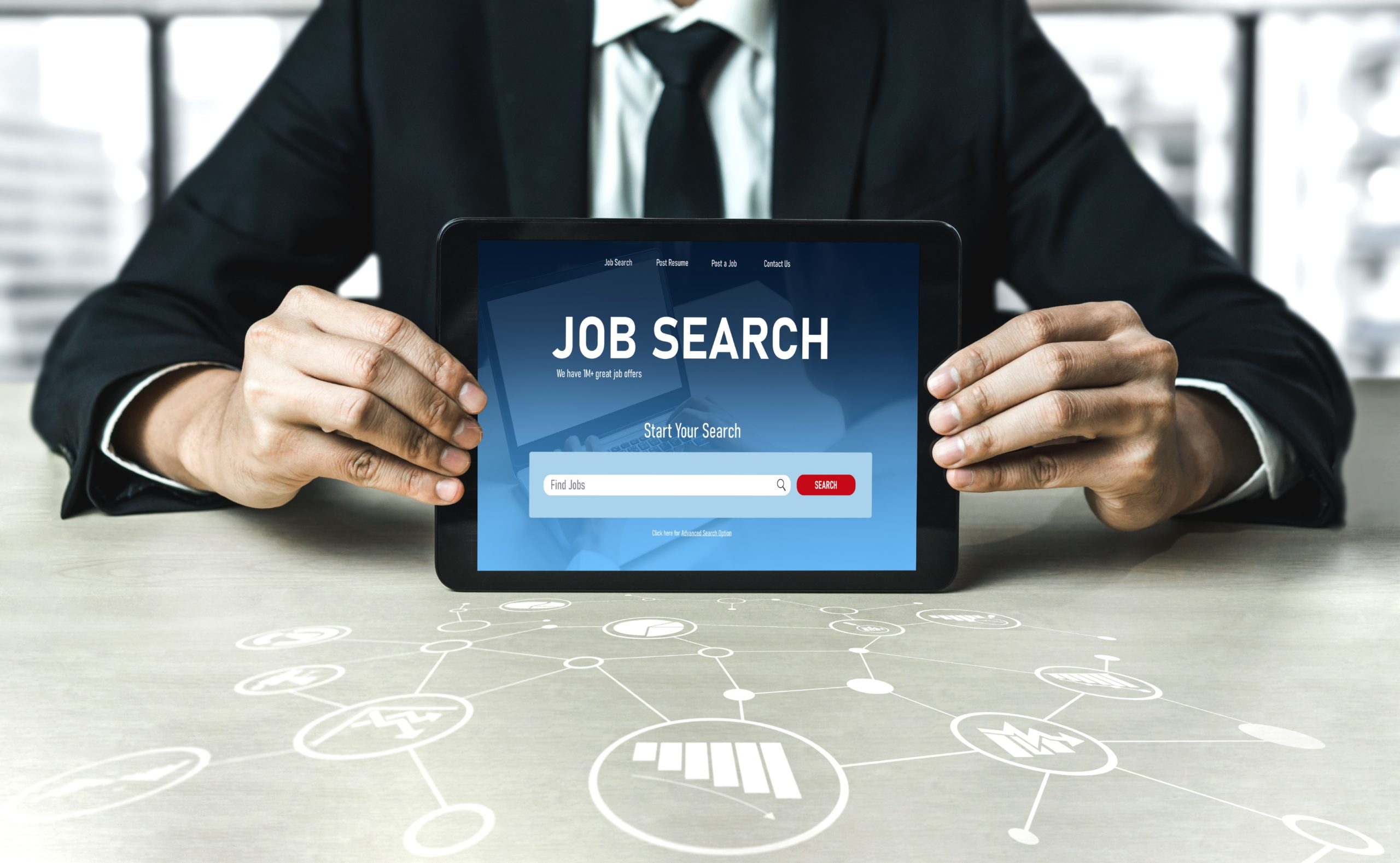 A suited up man is holding tablet device to show UAE job portal.